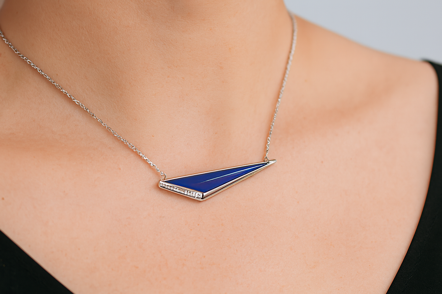 Blue triangular pendant necklace being worn