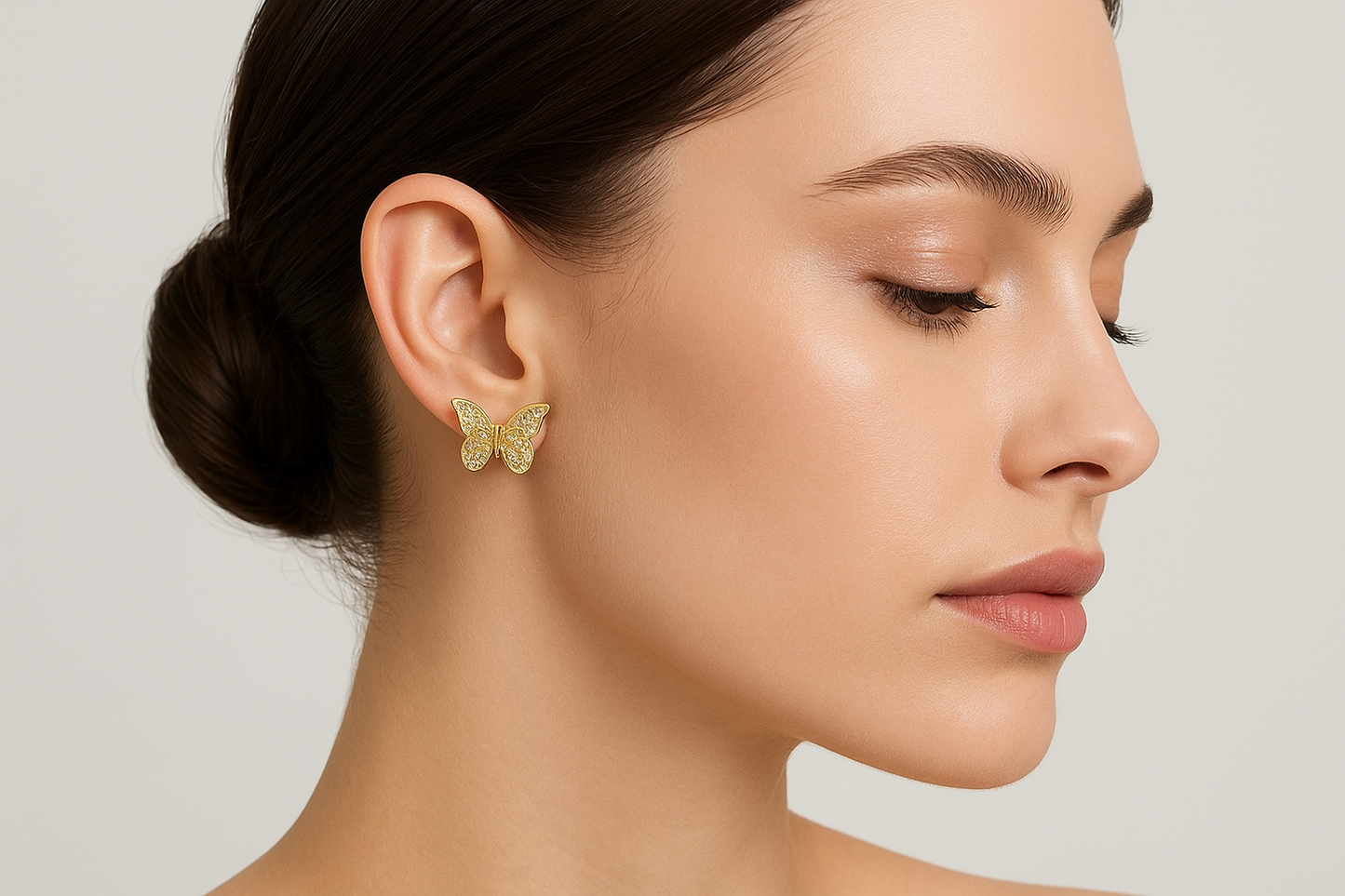 Model wearing gold butterfly stud earrings with crystal pavé detailing