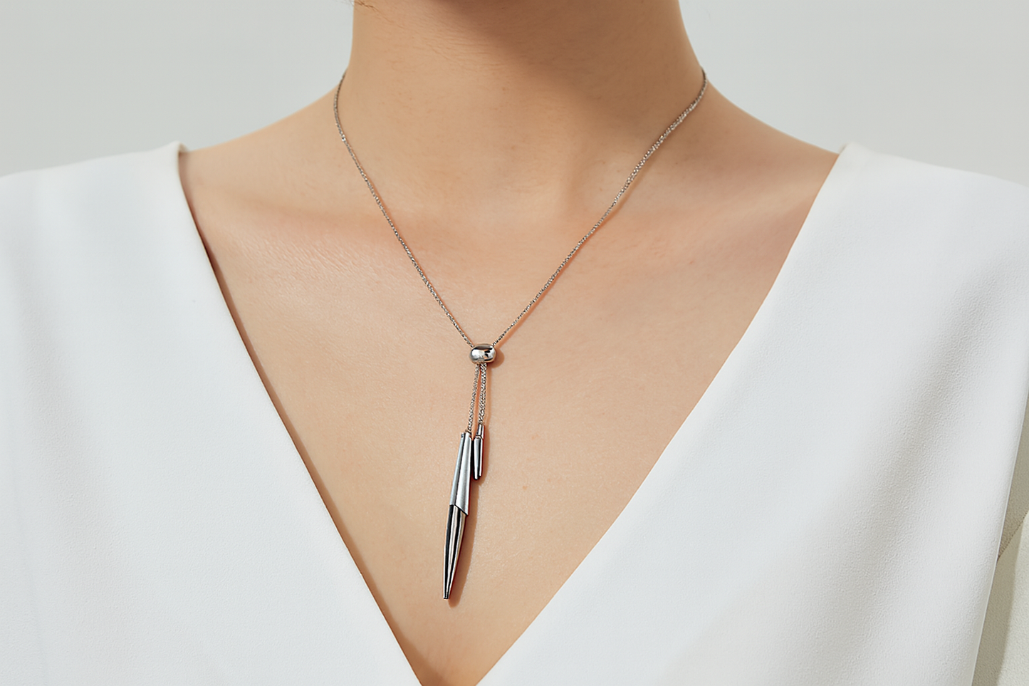 Modern silver necklace with dangling pendants being worn