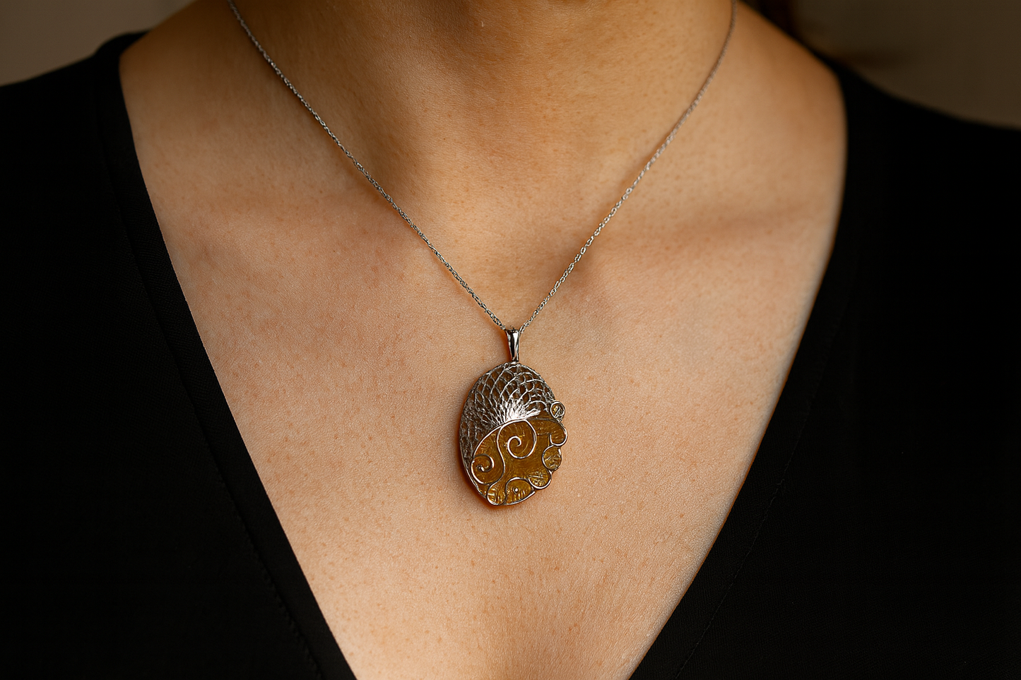 Artistic pendant necklace with lattice and golden swirls being worn