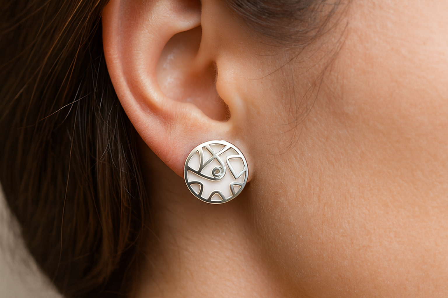 Elegant silver geometric earrings with white enamel and crystal centers being worn