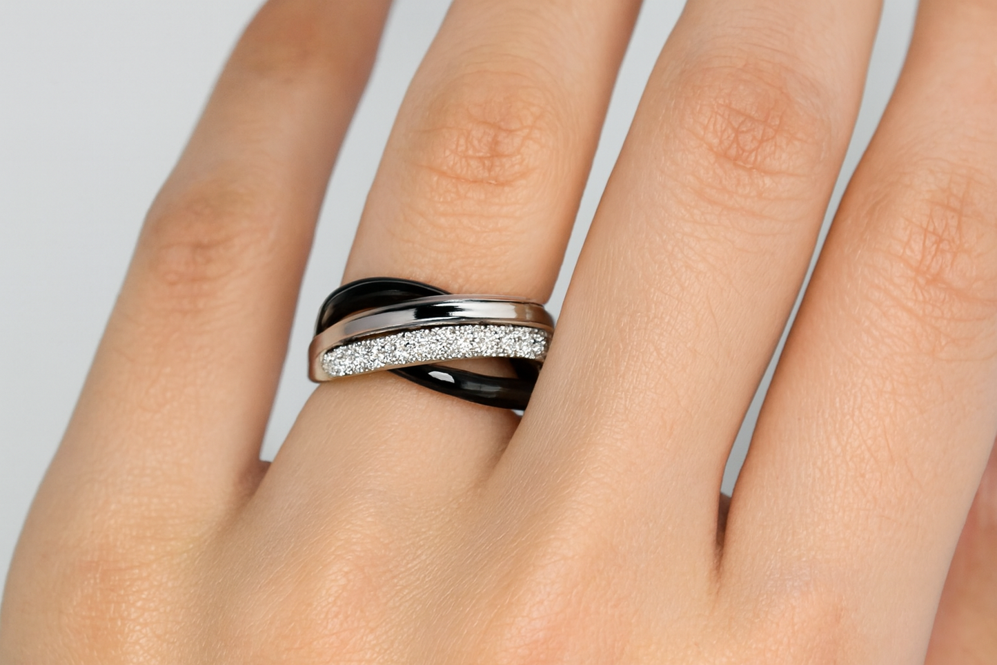 Elegant three-band interlocking ring with black, silver, and crystal elements being worn on hand