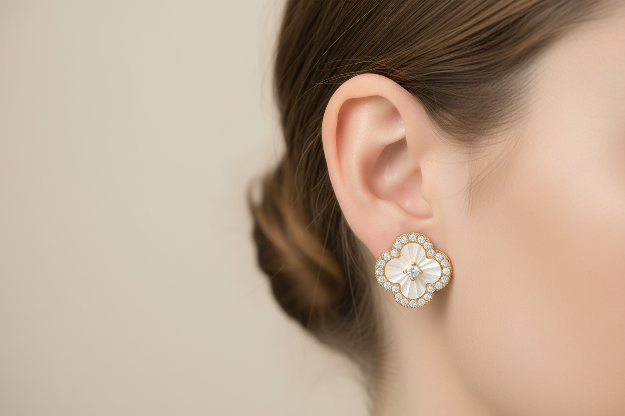 Gold clover mother of pearl earrings on model ear