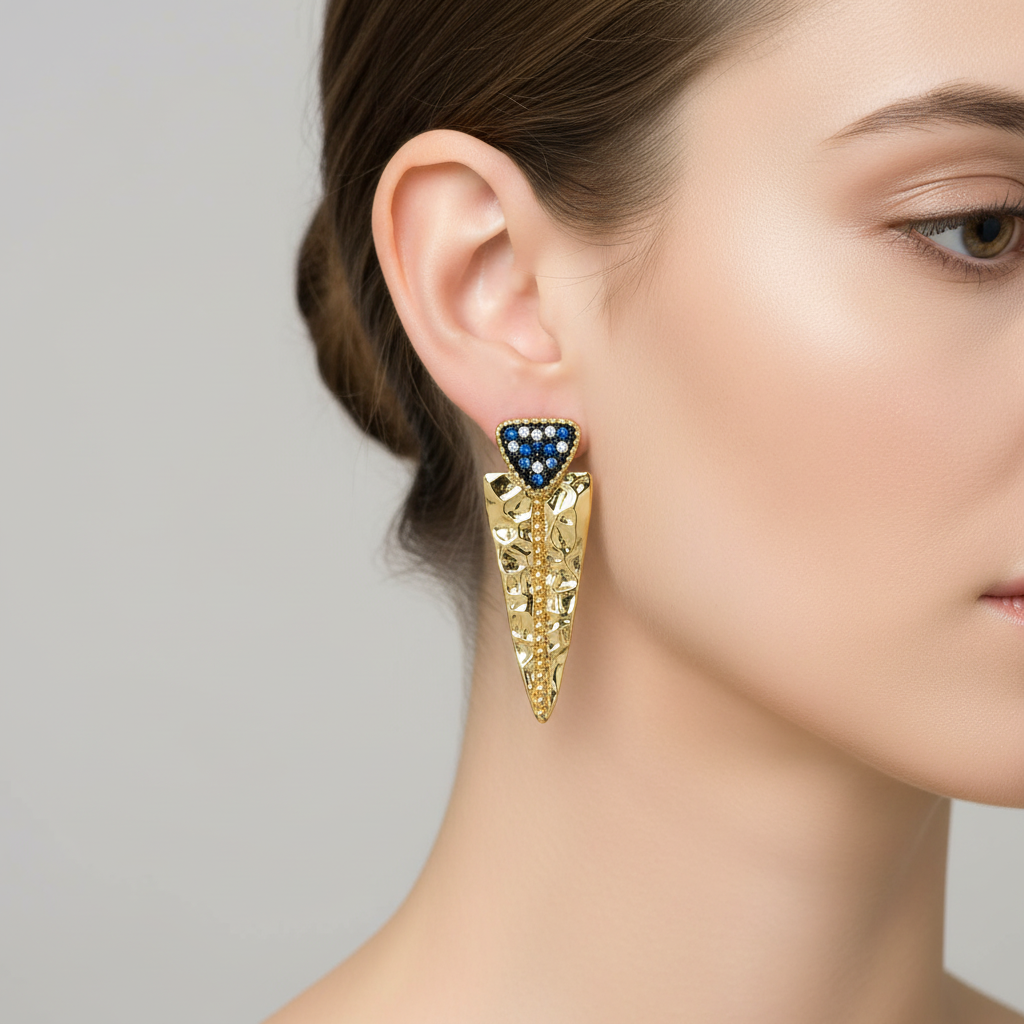 Gold filigree drop earring with blue stones on model ear