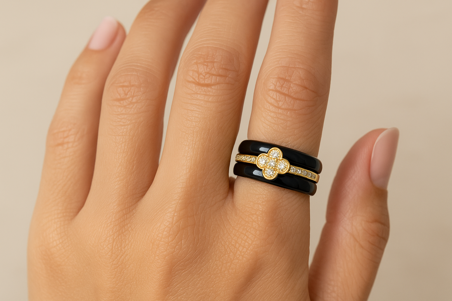 Model wearing black ceramic ring with gold crystal clover design