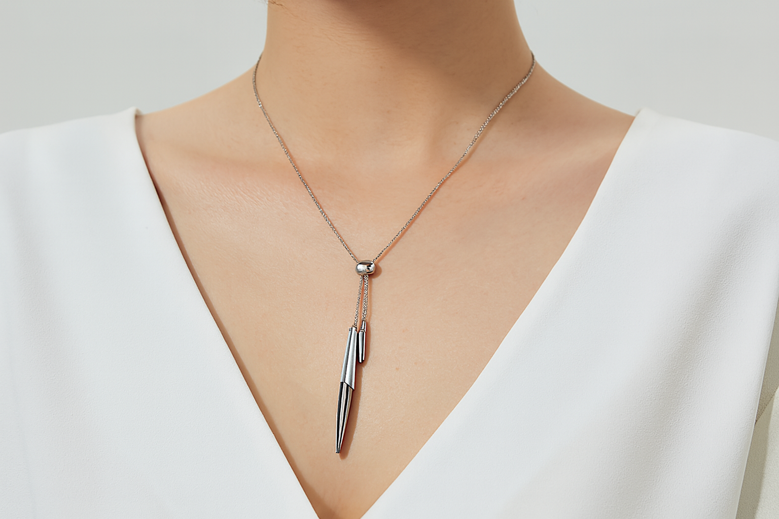 Modern silver necklace with dangling pendants being worn